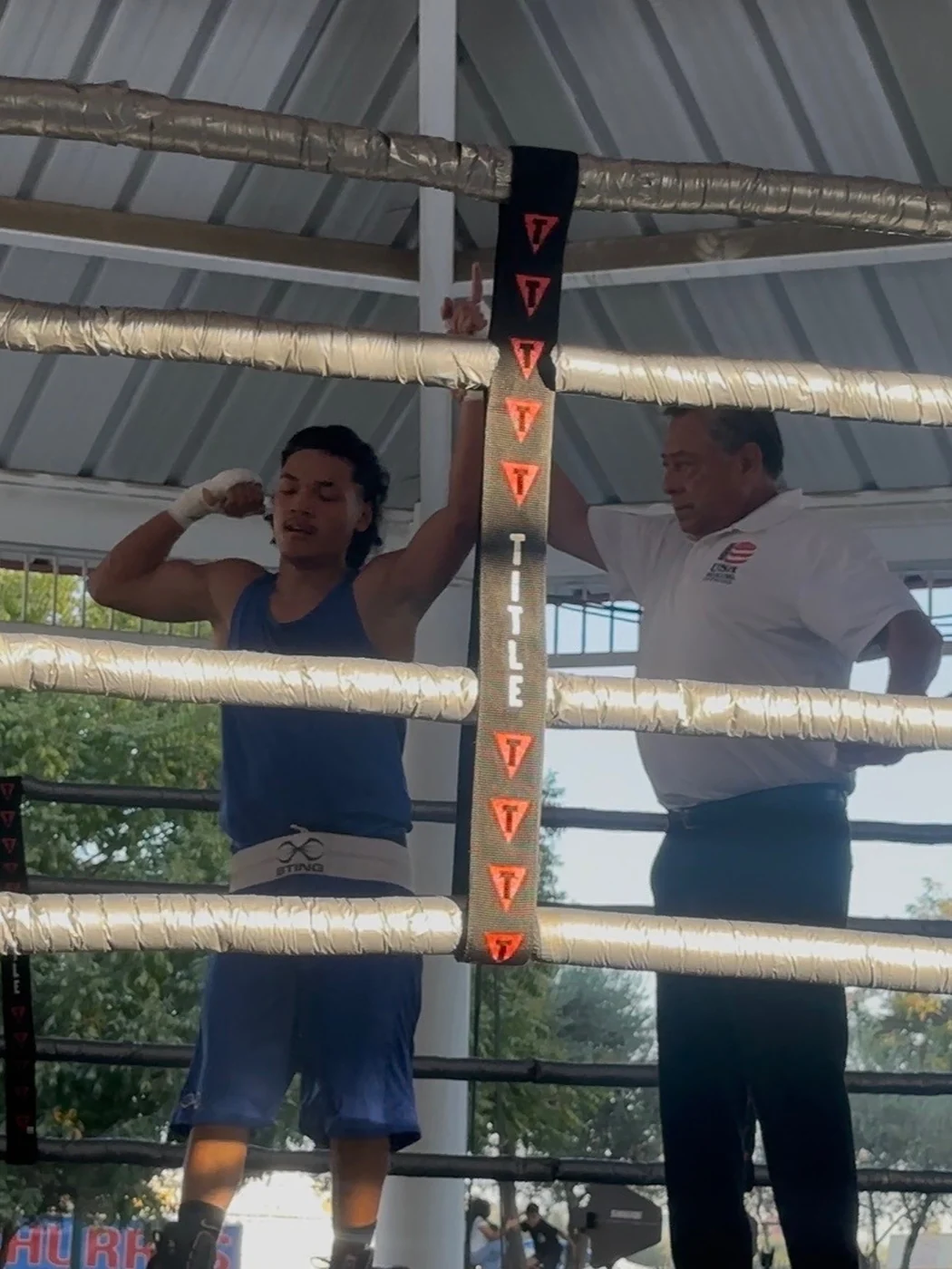 Fresno PAL boxer Isaya Pomul in the ring with his arm raised by the referee after his win at the Big Fresno Fair