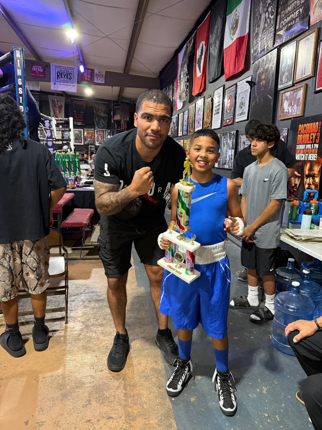 Fresno PAL boxer Jayad Gonzales holding his trophy beside his coach at the Aleman's Boxing Show
